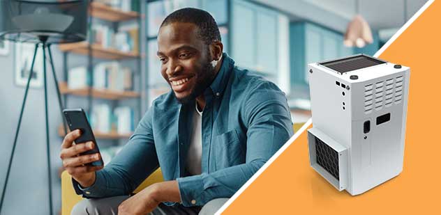 Man happily looking at his mobile phone. A gas heater appears on the right of the image.