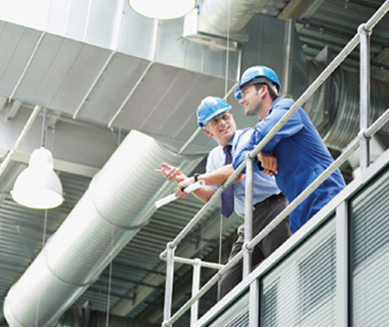 Two persons with construction hats on talking on the railing