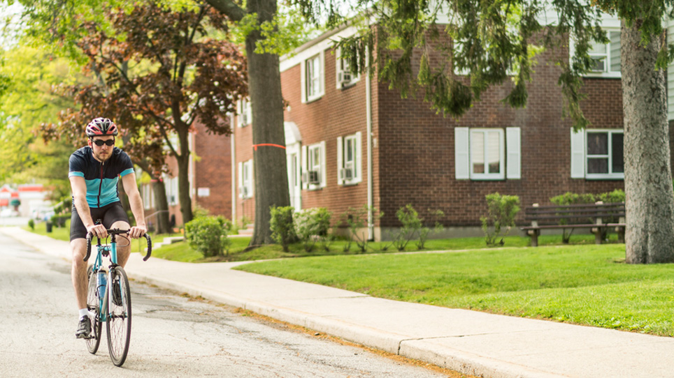 man riding his bike along a multifamily complex